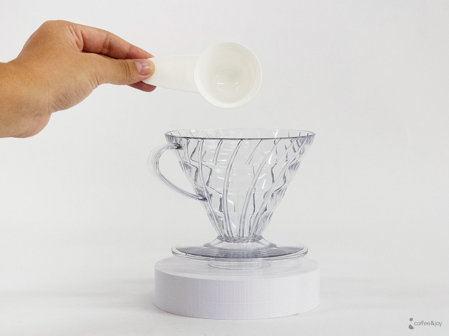 Proporção de água no preparo de café V60, com medidor despejando água no filtro para extração correta do café.